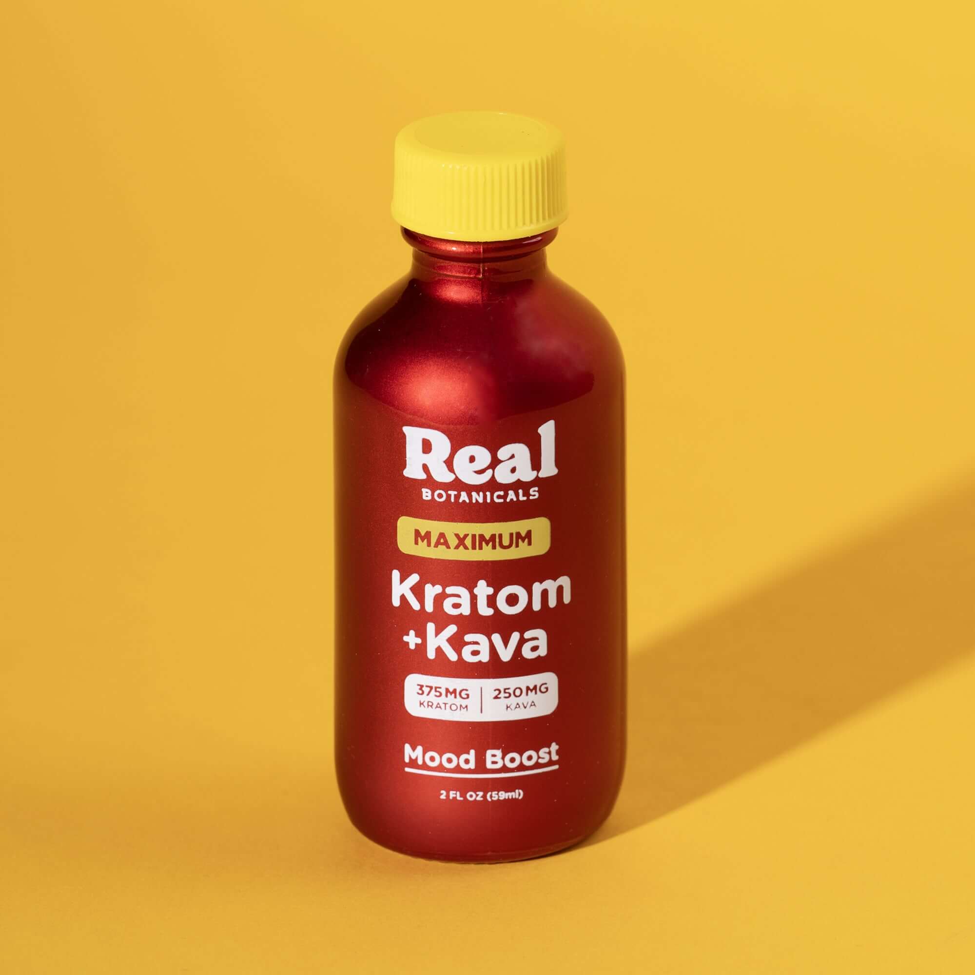 Front of Real Botanicals Maximum Mood Boost Shot bottle featuring red label with βKratom + Kavaβ and βMood Boostβ text, shown against a yellow background.